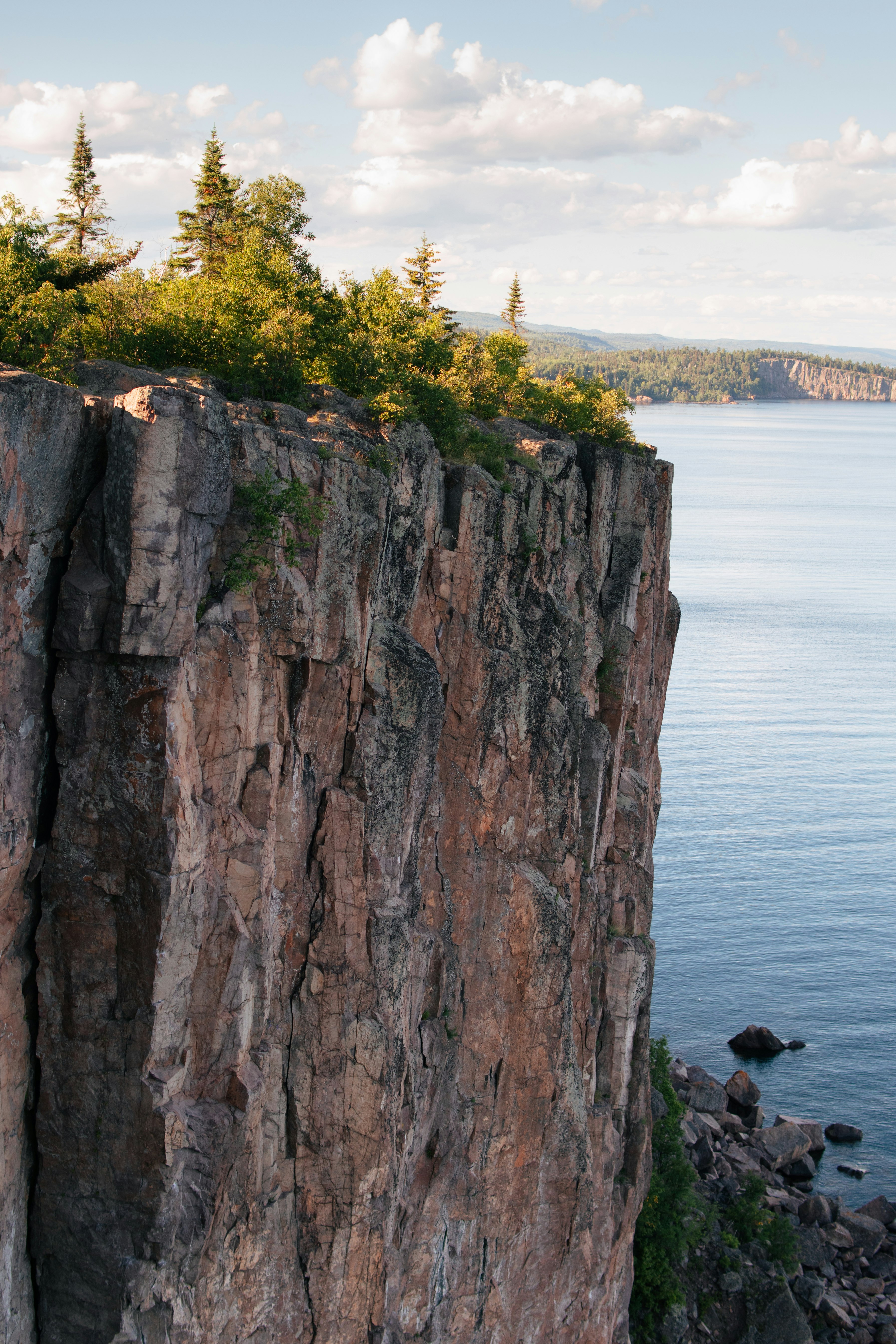 person sitting on rock formation near body of water during daytime